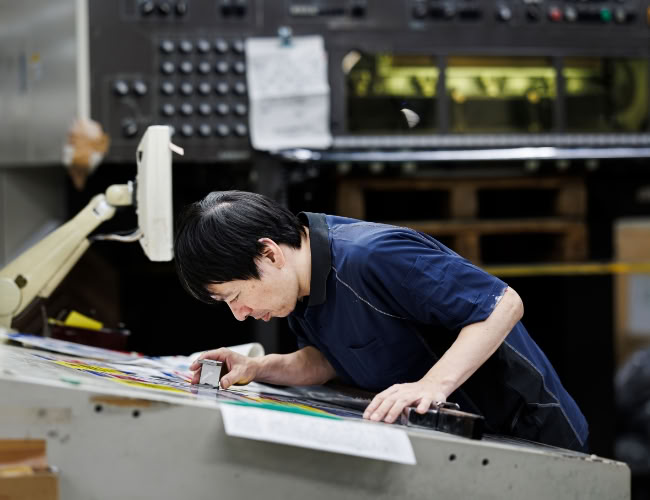 印刷機で刷り出しを確認する社員の様子