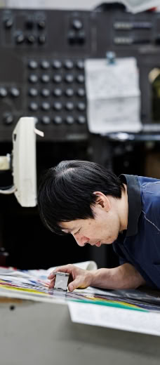 刷り上がった印刷物をルーペで確認するスタッフ