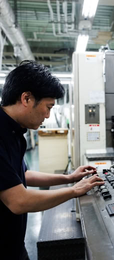 印刷機の操作パネルを操作するスタッフ